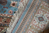 Ivory fringe, Perpedil motif on powder blue pile, and woven selvage of the vintage Indian carpet.