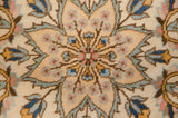 The central starburst medallion with blush, indigo, and mint green floral buds on a dense ivory pile.