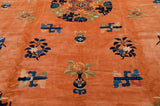 Angled view of a vintage Peking carpet's plush copper pile with traditional indigo blue motifs.