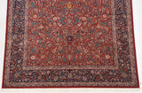 Close-up of vintage Chinese Isfahan carpet corner with cherry red arabesque field and navy blue floral border.