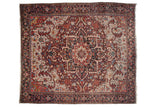 A vintage Persian Heriz carpet with a large center medallion and serrated leaf spandrels in gem-like shades of wine red and indigo blue.