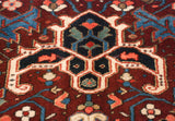 Close-up of a geometric palmette motif in navy blue, wine red, and sand on a Collector Heriz carpet.