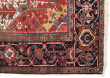 Intricate corner spandrel and navy floral border of a vintage Heriz carpet with intact white fringe.