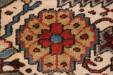 A precisely woven floral blossom in gem tones on the full, hand-knotted pile of a collector Heriz carpet.