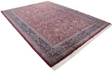 Angled view of the vintage Indian Kashan carpet's burgundy field and intricate navy blue border.