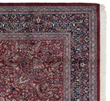 Detailed corner of a vintage Kashan carpet with a navy arabesque border and clean, original fringe.