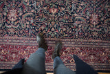 Hand knotted Indian Kashan rug displaying navy blue floral field and rich burgundy border.
