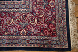 Indian Kashan carpet corner with burgundy floral arabesques, navy border, slate patterns, and fringe.