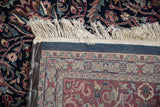 Hand-knotted vintage Indian Kashan carpet detail: fringed edge, navy floral pattern, and woven foundation.