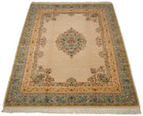 An angled view of the vintage Bulgarian carpet's floral medallion, corner spandrels, and ivory field.