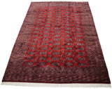 Angled perspective of a vintage Pakistani carpet with repeating cherry red guls and detailed borders.