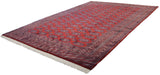 Angled view of a vintage Pakistani carpet with repeating Turkmen guls on a rich cherry red field.