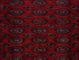 Intricate Turkmen guls in navy blue and silver against the carpet's dense cherry red pile.