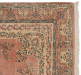 Vintage Indian Kerman rug corner, showing dusty rose field, scalloped border, floral vines, and fringe.