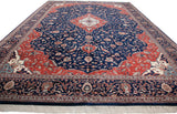 Angled perspective of a vintage Indian carpet highlighting its plush navy pile, red spandrels, and ivory fringe.