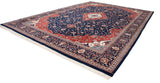 Angled view of an entire vintage Indian Kashan carpet, showing its red spandrels and navy floral field.