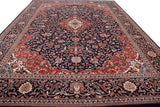 Delicate scrolling vinery on the navy field and red spandrel of the Kashan design rug.
