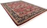 A vintage Agra carpet's angled view displays its elaborate cherry red and navy floral design.