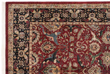 Intricate corner of a vintage Agra carpet featuring a navy floral border and cherry red field.