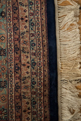 Ardebil design carpet's navy blue border, blush floral motifs, and intact ivory selvage.
