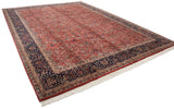 Angled perspective of a vintage Agra carpet showing the full brick red field and navy blue border.