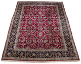 Angled view of a vintage Persian Kerman carpet, showing its dense floral pattern and navy border.