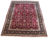 The expansive cherry red field and detailed navy border of a large vintage Kerman carpet.