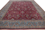 Angled perspective of a vintage Kerman carpet, highlighting its plush cherry red pile and floral sky blue border.