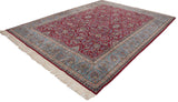 Vintage Kerman carpet from an angle, showcasing the cherry red floral field and sky blue border.