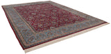 Angled view of a vintage Kerman carpet's cherry red field and wide, sky blue floral border.