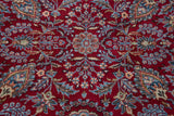 Central floral medallion in sky blue and apricot on a lush, cherry red wool pile.