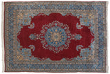 Cherry red field, blue floral corner spandrel, and meandering vine border on Kerman carpet.