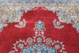 Cherry red Kerman carpet corner with sky blue floral spandrel and vine border.