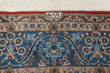 Vintage Kerman carpet border close-up with weaver signature, white fringe, red selvage, and blue meandering floral design.