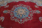 Vintage Kerman carpet: cherry red field featuring blue and beige floral motifs.