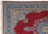 Corner of Vintage Kerman carpet, cherry red field, blue spandrel with meandering vine border.
