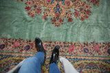A vintage Kerman carpet's soft, full pile in pale ocean green, with a detailed floral border.