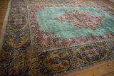 A vintage Kerman carpet's elaborate floral borders and medallion seen from a low corner angle.