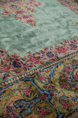 Soft, full pile of a vintage Kerman rug detailing the Rococo floral border beside the ocean green field.