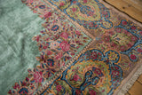 Corner detail of a vintage Kerman carpet with a Rococo-style floral border and pale green field.