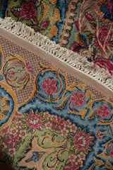 Corner view of a vintage Kerman carpet revealing the intricate trellis design on its woven back.