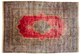 Fine Cyrus Crown Kerman carpet with a Rococo medallion on a saturated red field and elaborate blue and ivory floral borders.