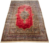 Angled view of a fine Kerman carpet, emphasizing its lustrous red field and intricate Rococo-style borders.