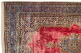 Corner of a vintage Kerman carpet showing the elaborate blue arabesque border and ivory floral spandrel.