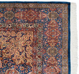 Corner of a vintage Pakistani Ardebil rug showing the intricate floral borders, indigo selvage, and white fringe.