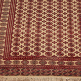 Close-up on the corner of a Pakistani Bokhara carpet, with detailed red borders and ivory fringe.