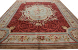 Low angle view of a vintage Savonnerie carpet showing its lustrous red field and grand scale.
