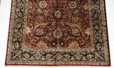 Corner of a vintage Indian Isfahan carpet, detailing the navy blue border and scrolling floral motifs.