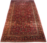 Angled view of a vintage Sarouk rug with intricate floral bouquets and sprays covering its long cherry red field.