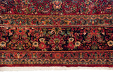 The fine floral border of a vintage Sarouk carpet, showing the dense wool pile and clean ivory fringe.
